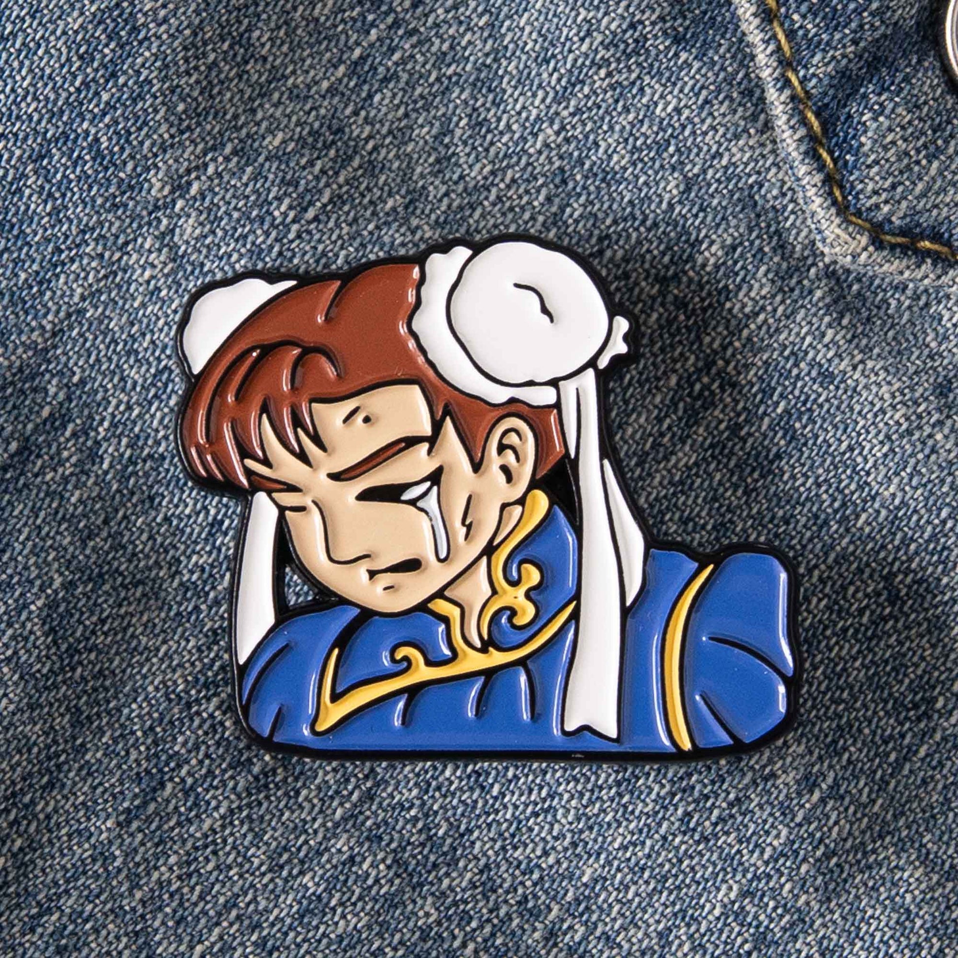 An enamel pin of the Street Fighter video game character, Chun Li, battered up. This pin design pays homage to the classic Street Fighter 2 game continue screen.