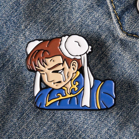 An enamel pin of the Street Fighter video game character, Chun Li, battered up. This pin design pays homage to the classic Street Fighter 2 game continue screen.